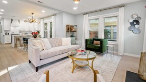 A modern living room with a sofa, coffee table, and a dining area with a bar. - The Hansel-Modern 4 Bed, 3 Bath Bungalow, Hot Tub (Dallas)