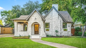A stone house with a central entrance, a small porch, and a well-maintained lawn. - The Hansel-Modern 4 Bed, 3 Bath Bungalow, Hot Tub (Dallas)