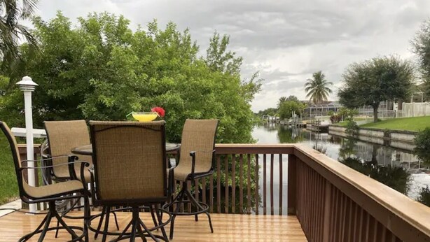 A wooden deck with outdoor furniture and a view of a water body. - Family Canal House/ Heated Pool, Kayaks, BBQ, Lift (Cape Coral)