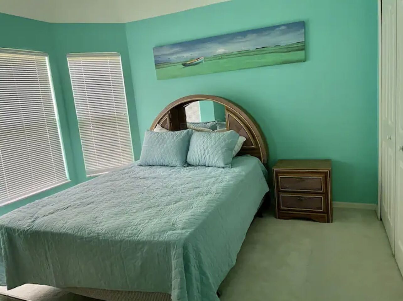 A bedroom with a bed, a nightstand, and a painting on the wall.