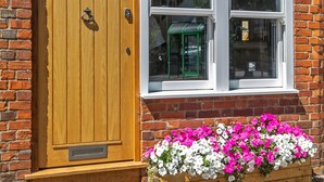 A brick building with a wooden door and a window. - The Nestle House (Winchester)