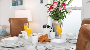 A breakfast table set with croissants, orange juice, and a vase of flowers. - The Nestle House (Winchester)