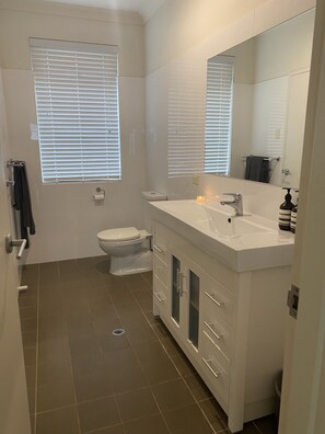 Un baño moderno con inodoro, lavamanos y espejo.