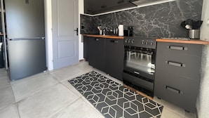 A modern kitchen with a black refrigerator, a built-in oven, and a marble backsplash. - Cap Corse, Sisco. Apartment in stone village house with sea view  (Sisco)