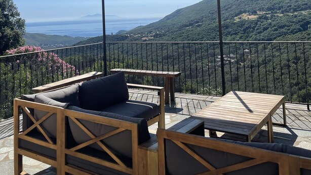 A terrace with wooden furniture and a large canopy, overlooking a scenic landscape with hills and a view of the sea. - Cap Corse, Sisco. Apartment in stone village house with sea view  (Sisco)