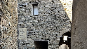 A stone building with a narrow passageway and a sign indicating a restaurant. - Cap Corse, Sisco. Apartment in stone village house with sea view  (Sisco)