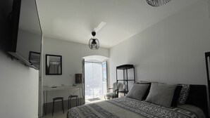 A bedroom with a bed, a desk, and a chair. There is a window with a view of the outside. - Cap Corse, Sisco. Apartment in stone village house with sea view  (Sisco)