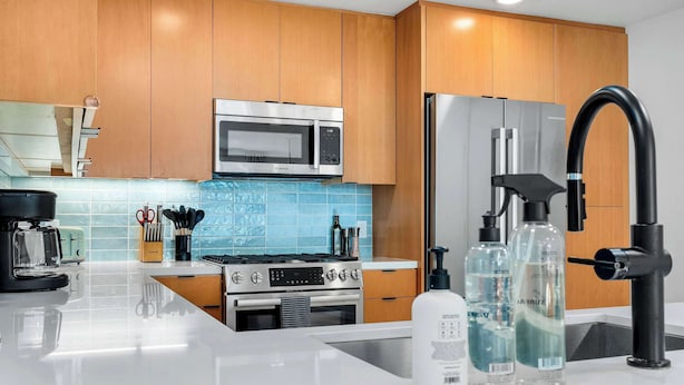 A modern kitchen with wooden cabinets, a stainless steel range, a microwave, and a sink with a faucet.