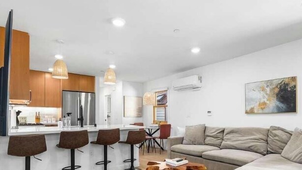 A modern kitchen with a central island, bar stools, and pendant lighting.