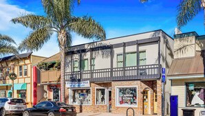 A street view with a two-story building featuring a storefront with a sign for a store closing sale.