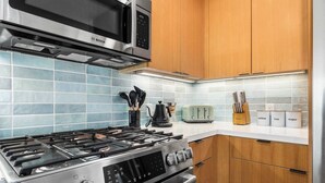 A modern kitchen with a stainless steel stove, a Bosch microwave, and wooden cabinets.