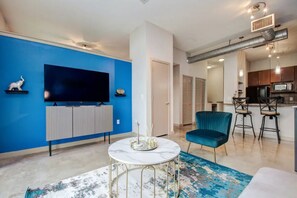 Relax in this stylish living room with a large flat-screen TV, round table, and comfortable armchair.