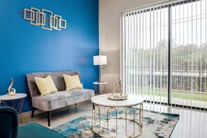 Relax in this stylish living room with a sofa, table, and lamp, surrounded by lush views.
