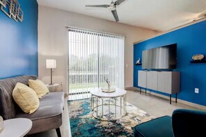 Relax in this stylish living room with a sofa, coffee table, and armchair, perfect for unwinding in front of the large flat-screen TV.