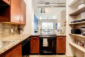 Functional kitchen with central stove, oven, and sink, perfect for cooking and food preparation.