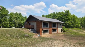 Une maison à deux étages avec un toit en pente, un porche à l’avant et une petite terrasse.