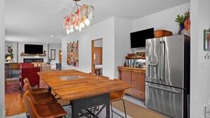 Une cuisine moderne avec un réfrigérateur en acier inoxydable, une table à manger en bois et des chaises rouges.