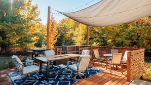 Une terrasse en bois, dotée de mobilier d’extérieur, d’un barbecue et d’un auvent.
