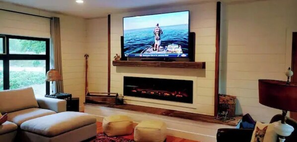 TV connectée, cheminée, livres, écrans d'ordinateur