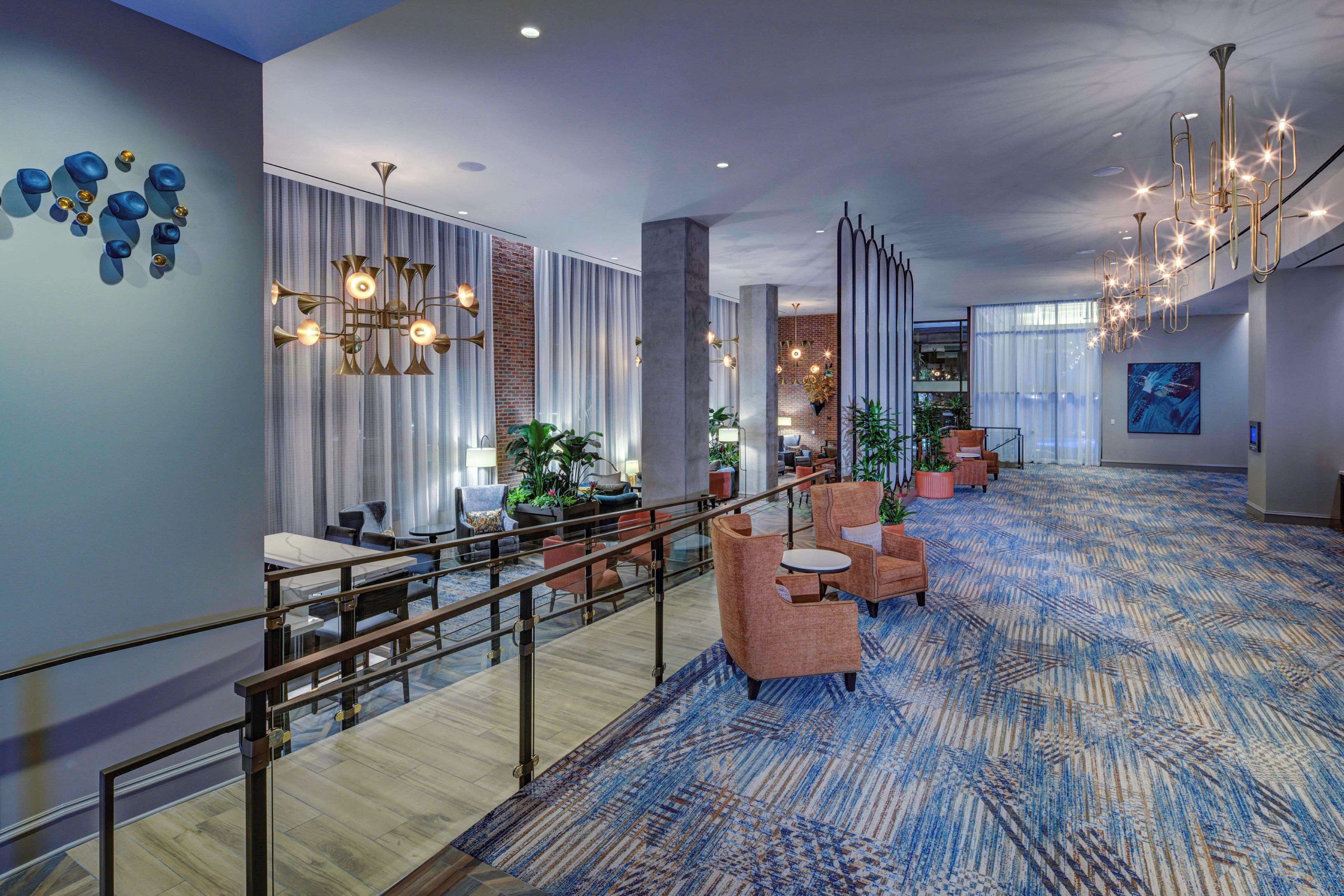 A spacious lobby with a high ceiling, modern lighting fixtures, and a patterned carpet.