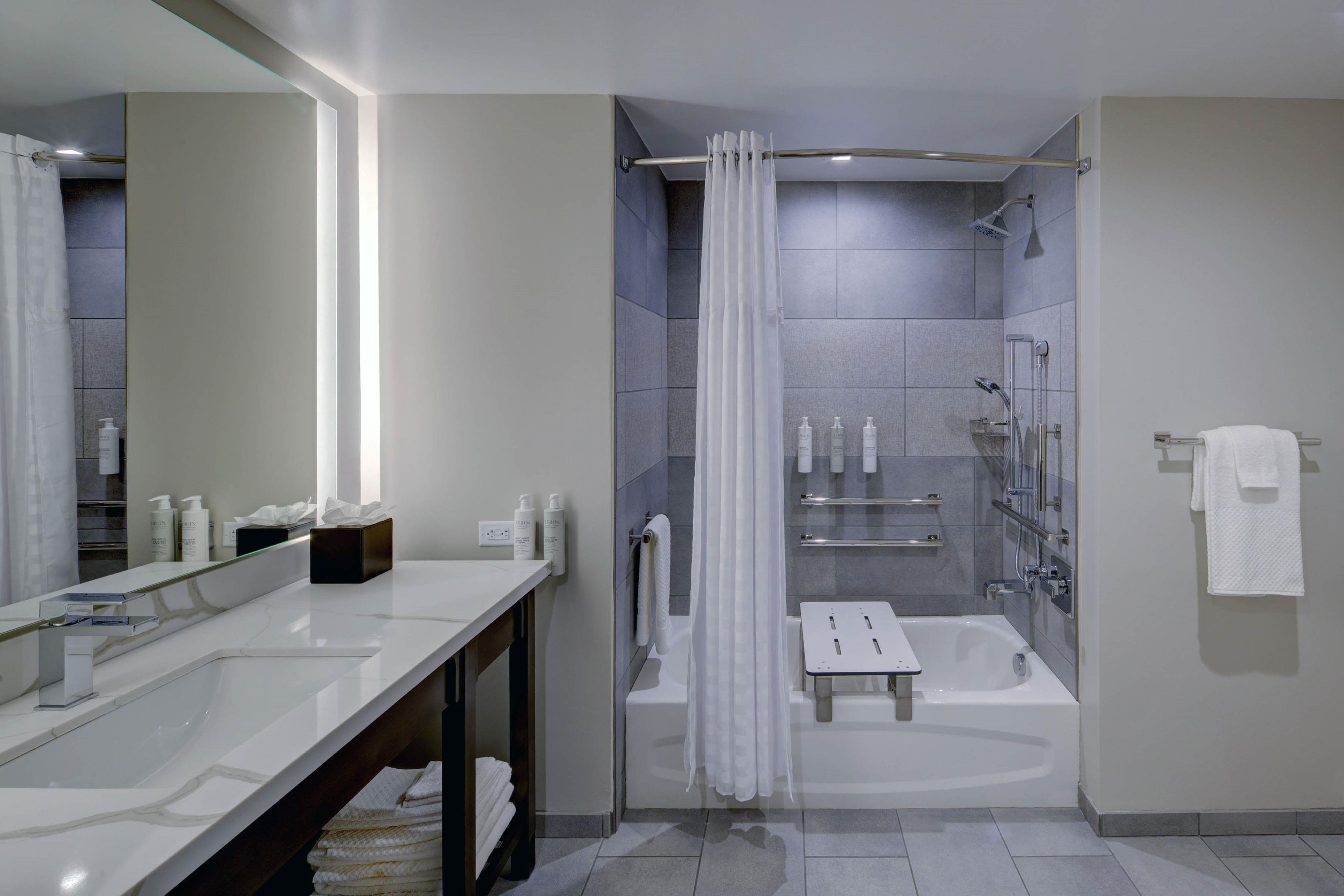 Un baño moderno con un espejo grande, dos lavabos, una ducha y una bañera.