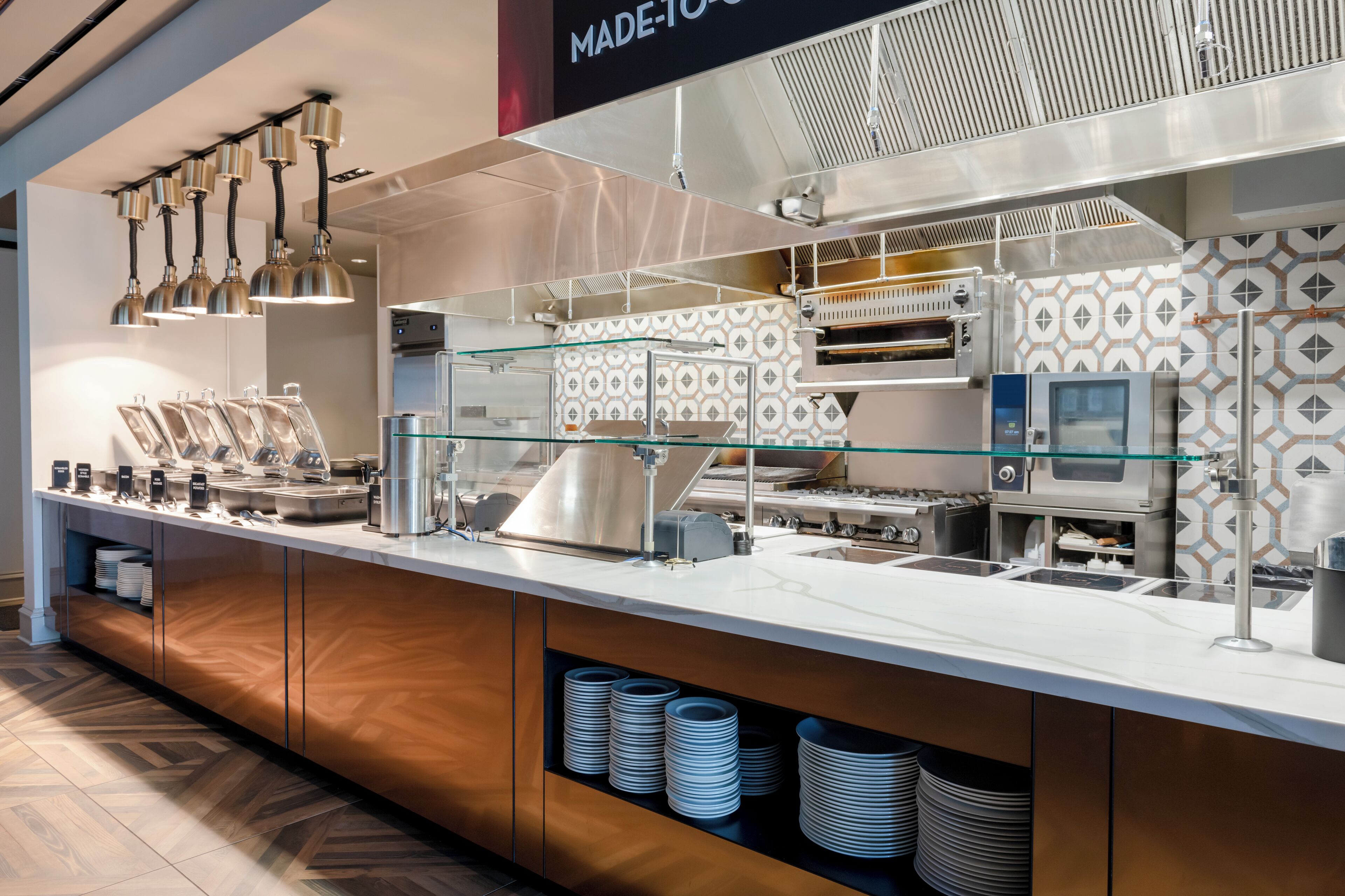 A buffet area with a stainless steel counter, multiple serving stations, and a patterned backsplash.