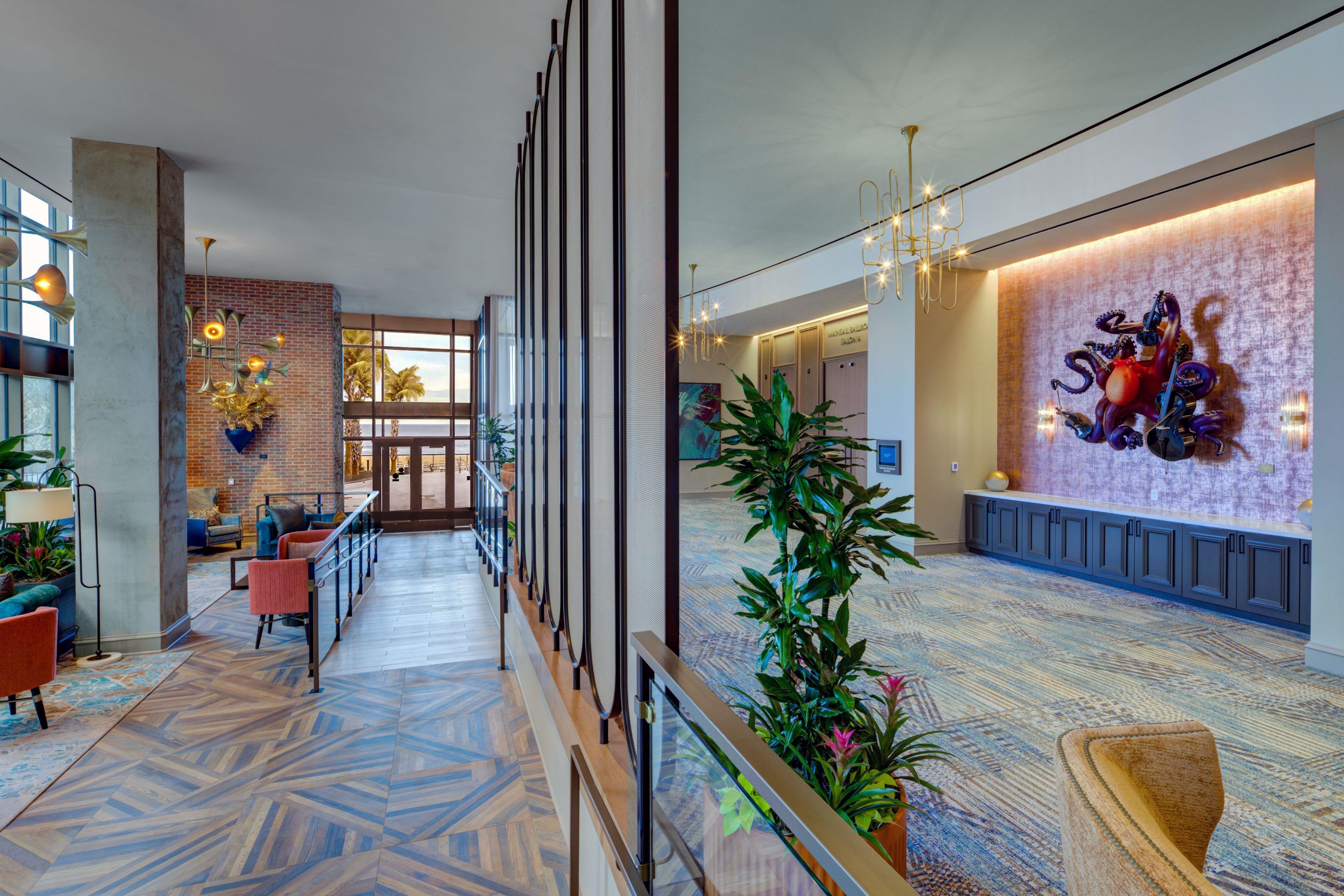 A spacious lobby with a modern design, featuring a patterned floor, seating areas, and a decorative wall with a unique sculpture.