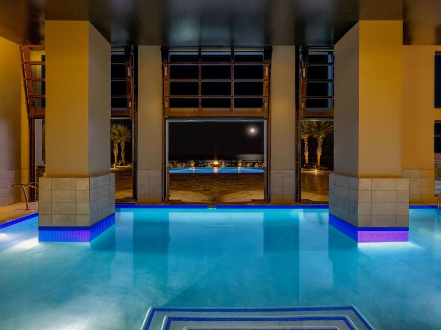 An indoor swimming pool with a view of the beach at night.