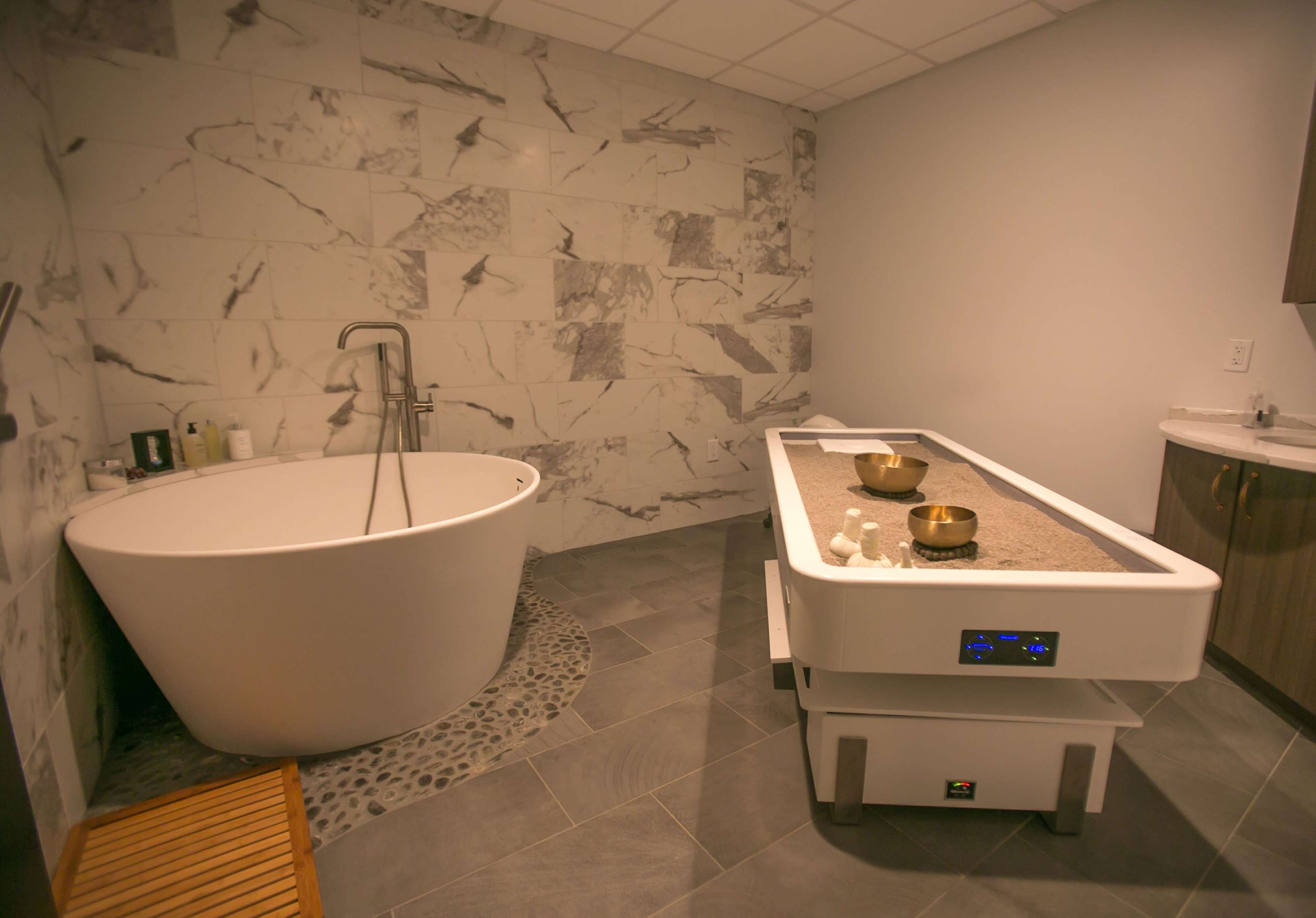 Une salle de bain moderne dotée d’une baignoire sur pieds, d’une douche intégrée et d’un espace lavabo séparé.