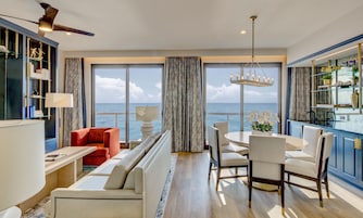 Uma sala de estar moderna com vista para o mar, uma área de refeições e uma cozinha com uma vitrine de vidro.