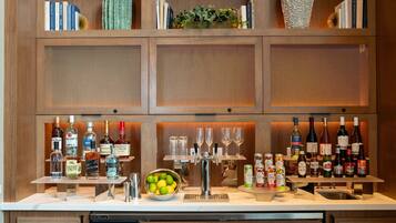 A bar area with shelves of liquor bottles, a fruit bowl, and a wine cooler.