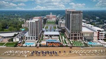 Un hotel con diversi edifici, una zona piscina e una spiaggia con lettini.