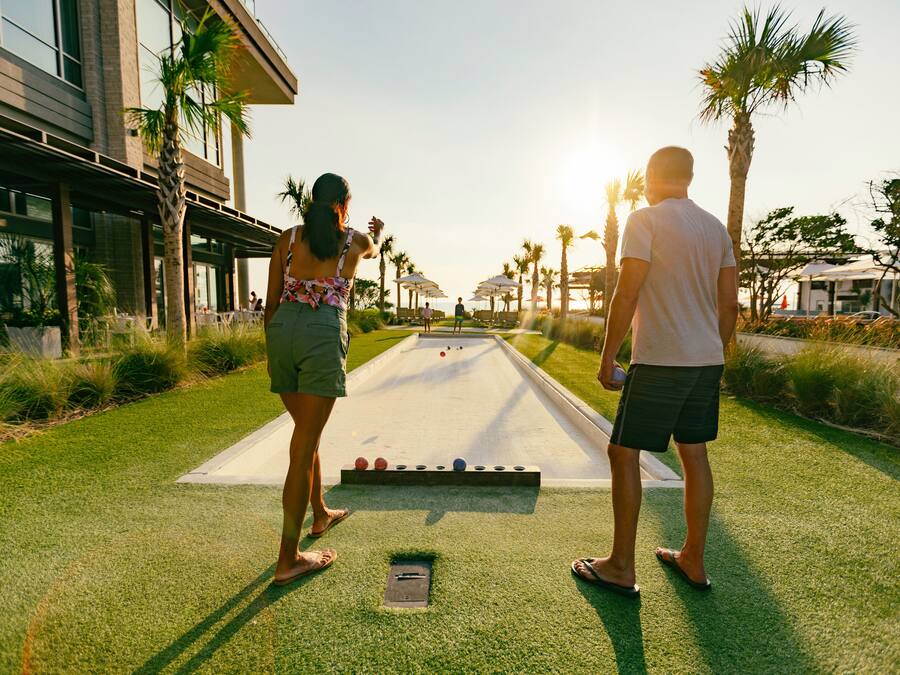 A croquet game on a green field with a building in the background.