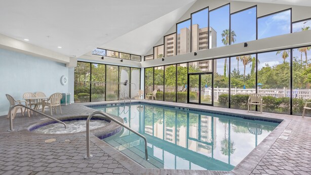 An indoor swimming pool with clear views of palm trees and buildings through large windows. - 1407 - Universal Studios View (Orlando)