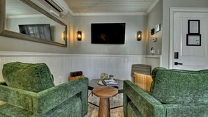 A room with green upholstered chairs, a wooden coffee table, and a flat-screen TV mounted on the wall. - Modern Penthouse Suite in historic downtown Blue Ridge, GA (Blue Ridge)