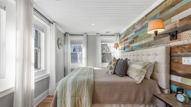 A bedroom with a large bed, a wooden headboard, a nightstand with a clock, and a window with curtains. - Modern Penthouse Suite in historic downtown Blue Ridge, GA (Blue Ridge)