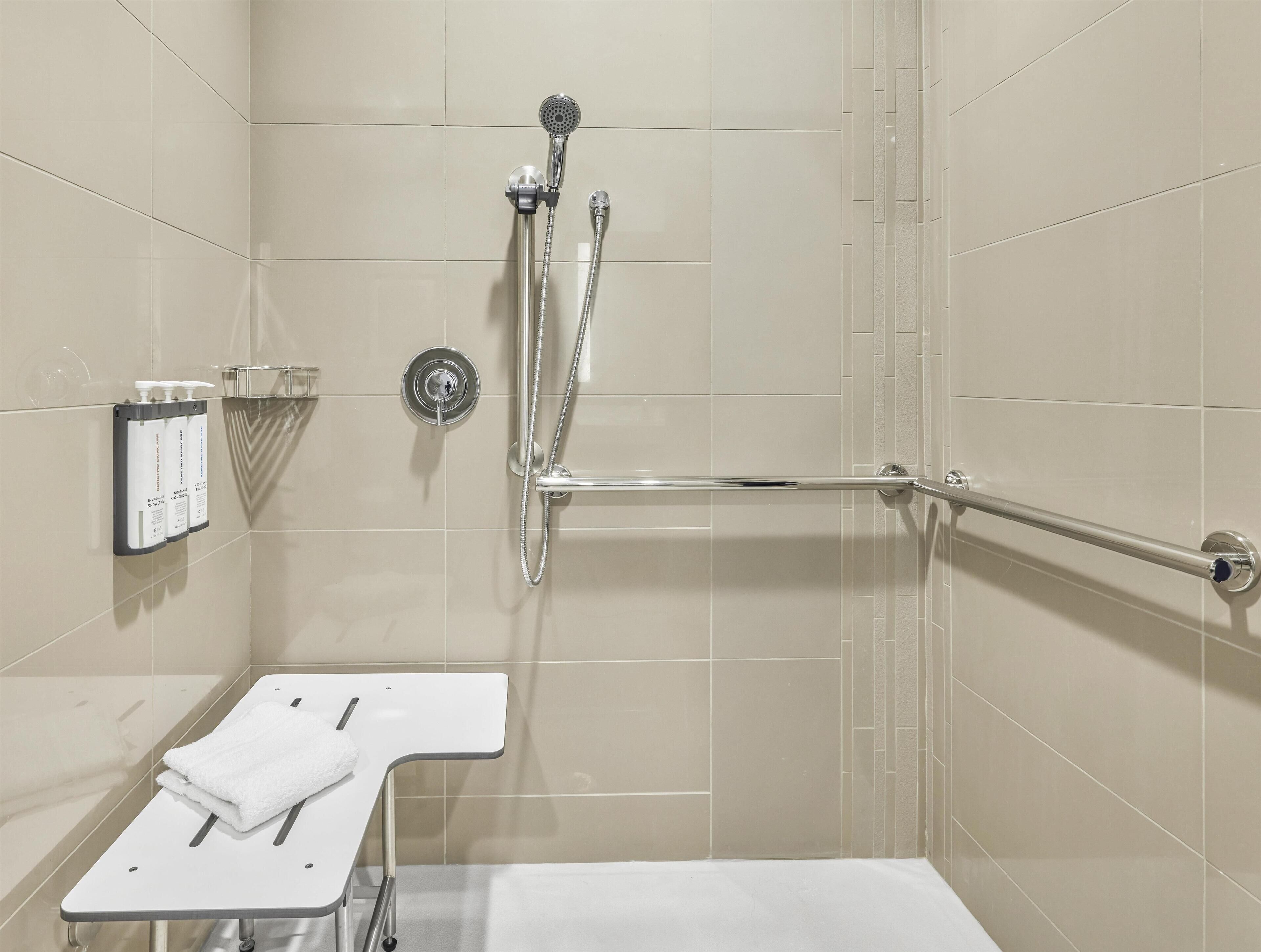 Un baño con ducha, secamanos y toallero.