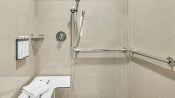 Un baño con ducha, secamanos y toallero.