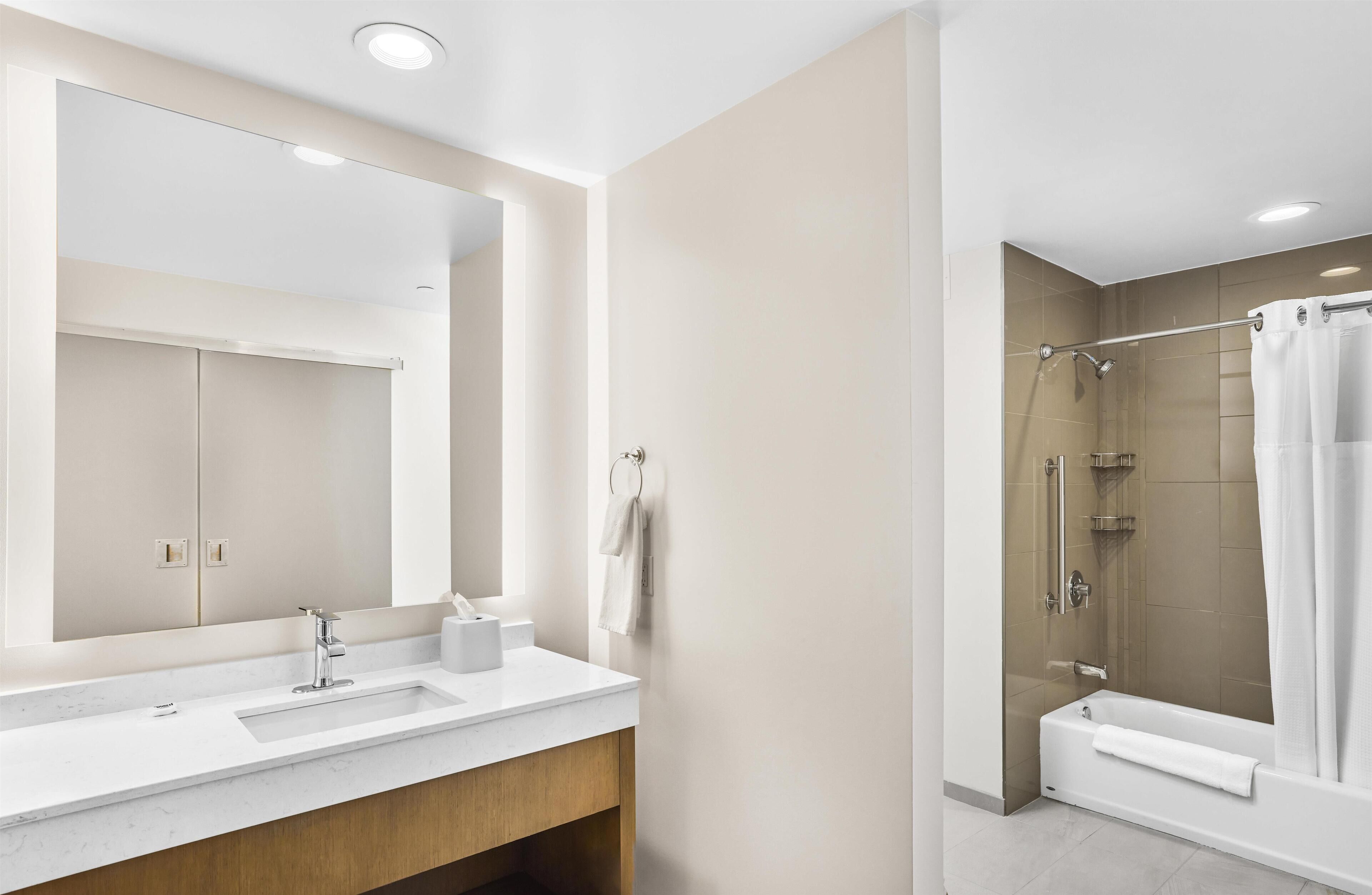 Une salle de bain moderne avec un grand miroir, un lavabo et un espace douche.