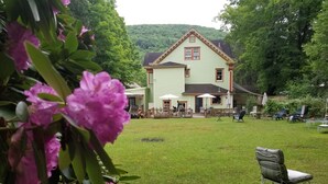 Ein grünes Haus mit Terrasse, Sitzgelegenheiten im Freien und einem Rasen.