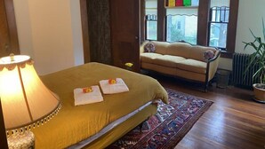 Ein Zimmer mit Bett, Schlafsofa, einer Deckenleuchte, einem Buntglasfenster und einer Heizung.