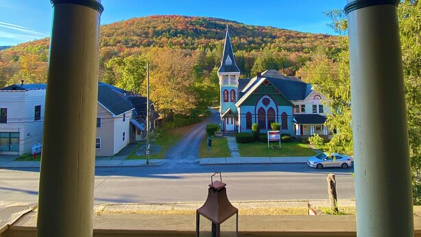 Blick durch einen Bogen mit einer hängenden Leuchte, einem dekorativen Tisch und einer Kirche mit Kirchturm im Hintergrund.