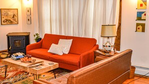 Ein Wohnzimmer mit einem roten Sofa, einem Holztisch, einer Lampe und einem Kamin.