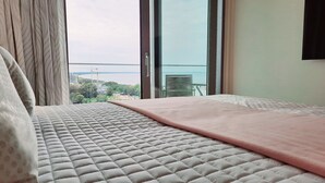 Ein Schlafzimmer mit Bett, Blick auf ein Gewässer und einem Balkon.