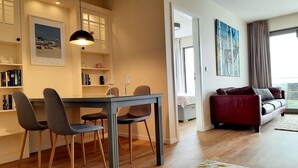 Ein modernes Wohnzimmer mit Essbereich, einem roten Sofa und Blick ins Freie.