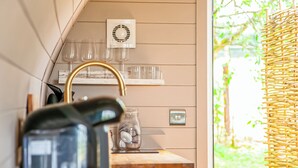 Een keuken met een waterkoker, een glazen pot en een lichtschakelaar aan de muur.