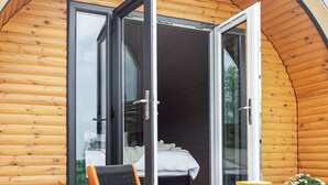 Een houten chalet met een grote schuifdeur die leidt naar een slaapkamer met een bed en een stoel.