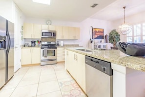Enjoy cooking in this well-equipped kitchen with a large island, sink, and stainless steel appliances.