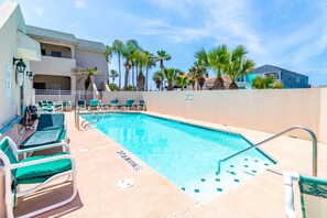 Un espace piscine avec des chaises longues et un panneau indiquant la présence d’un sauveteur.