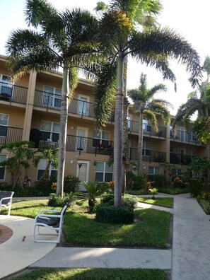 A multi-story building with balconies, surrounded by palm trees and greenery. - Relaxed Island Escape with Pool and Hot Tub Access (South Padre Island)